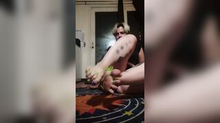 Gagged, she ties her foot with green string and stretches, wiggles and flexes until they break free