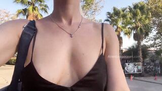 A sluts without lingerie inside outdoor, shining boobies strolling among strangers, not far from the sea.