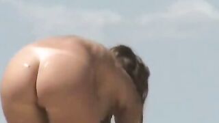 Un voyeur filme une jeune femme avec des gros seins sur la plage