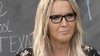 Blonde Teacher with Glasses Grades Papers in Classroom